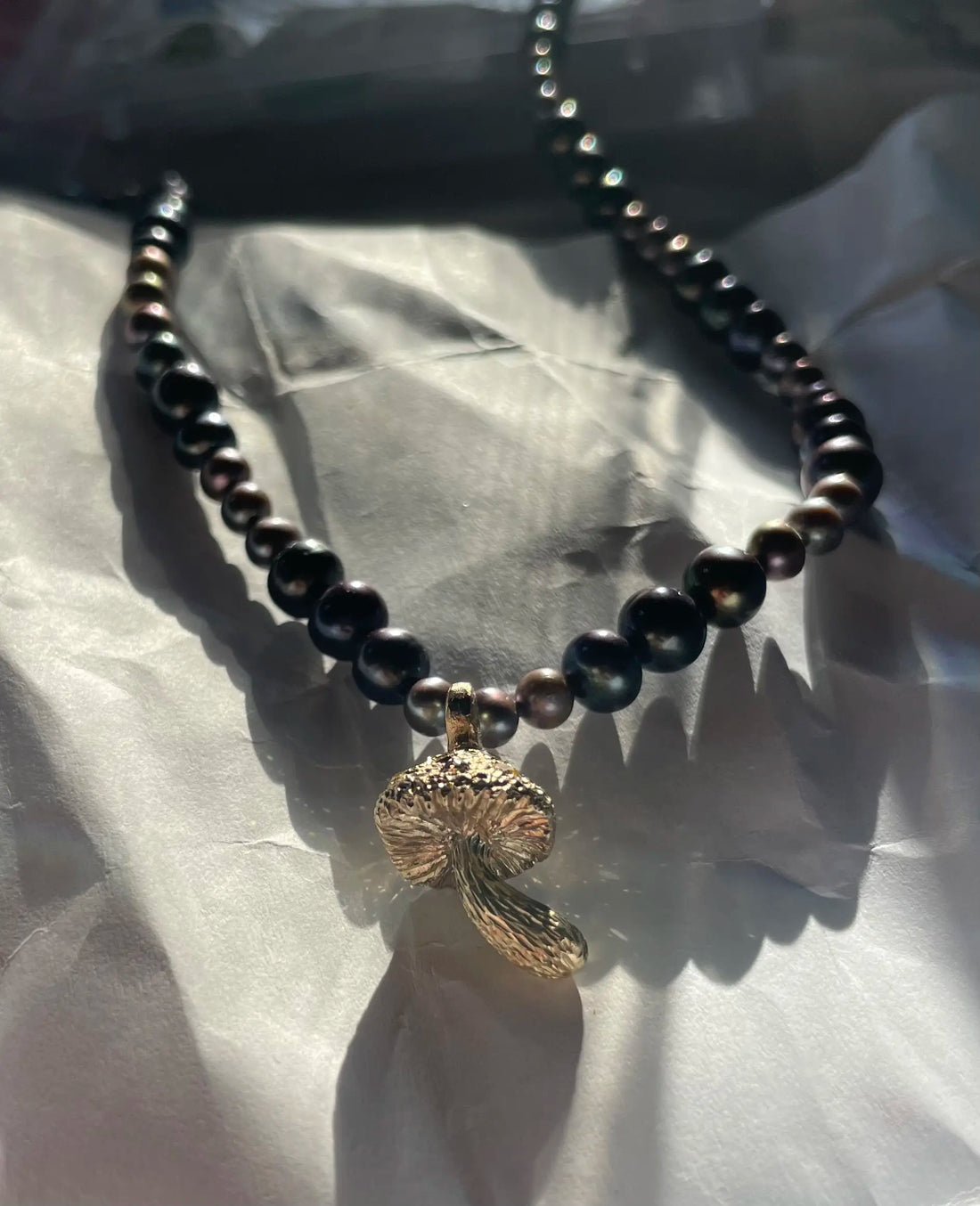 Necklace with black beads and a gold pendant on a white background