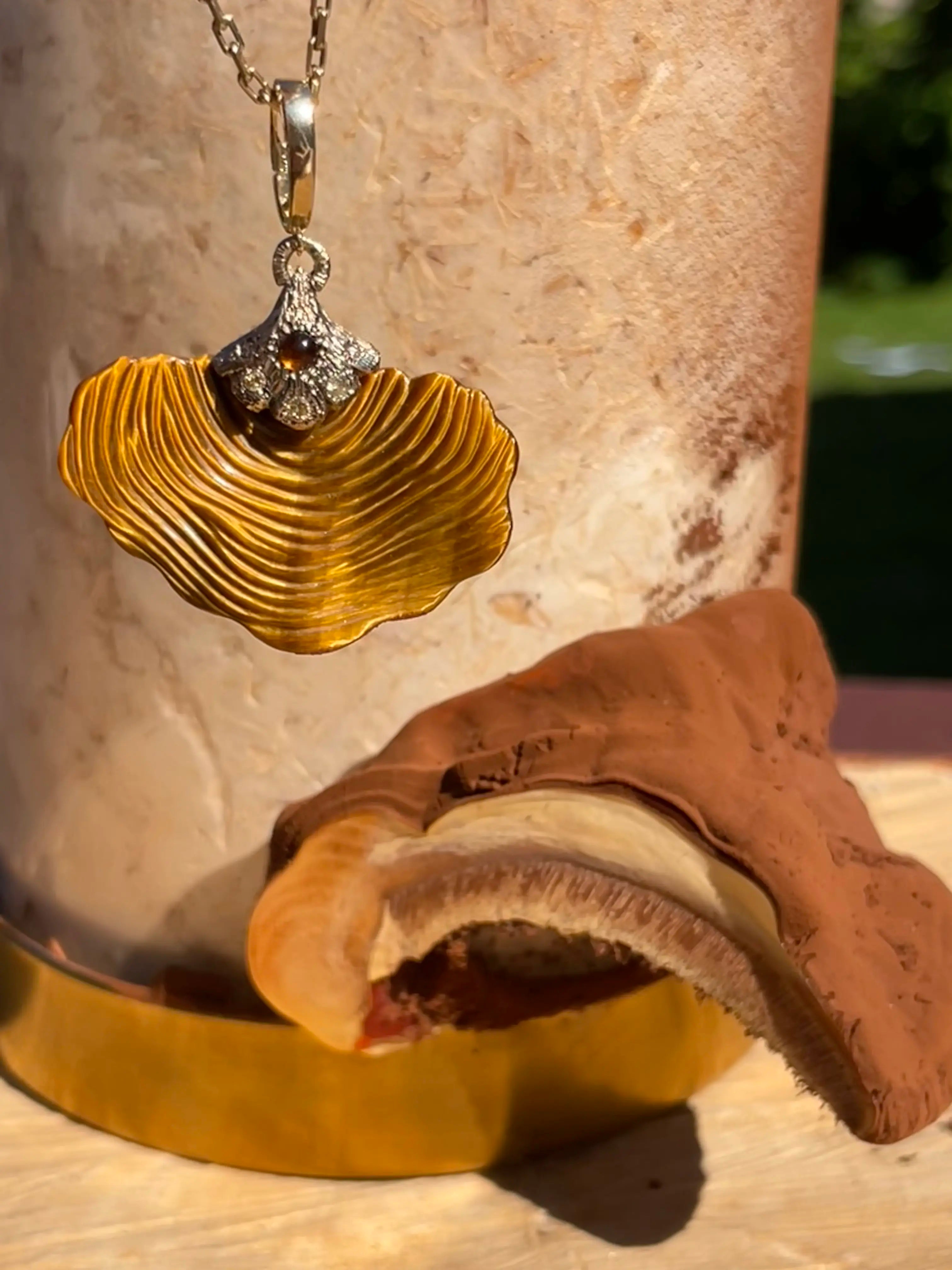 Gold shell pendant with a chain on a textured surface