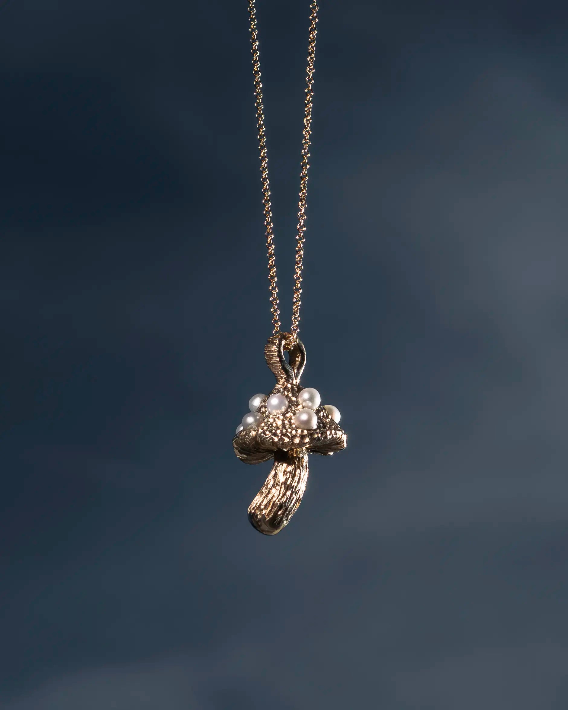 Gold necklace with a pendant on a dark background