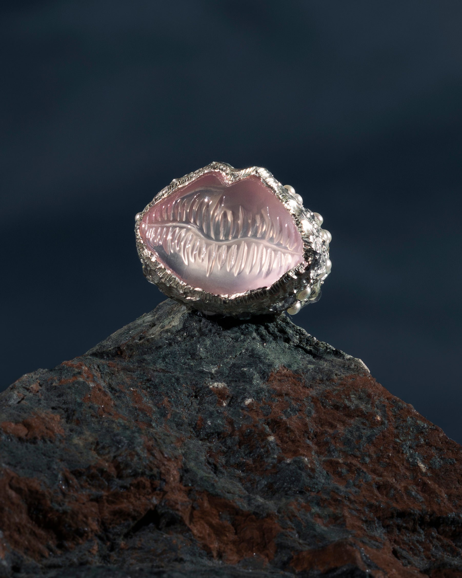 Silver ring with a pink stone on a dark background