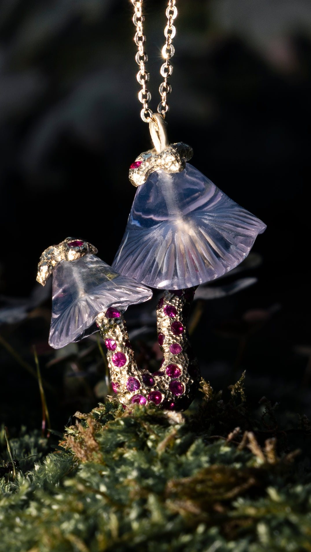 Transparent mushroom-shaped necklace with embedded gemstones on a dark background