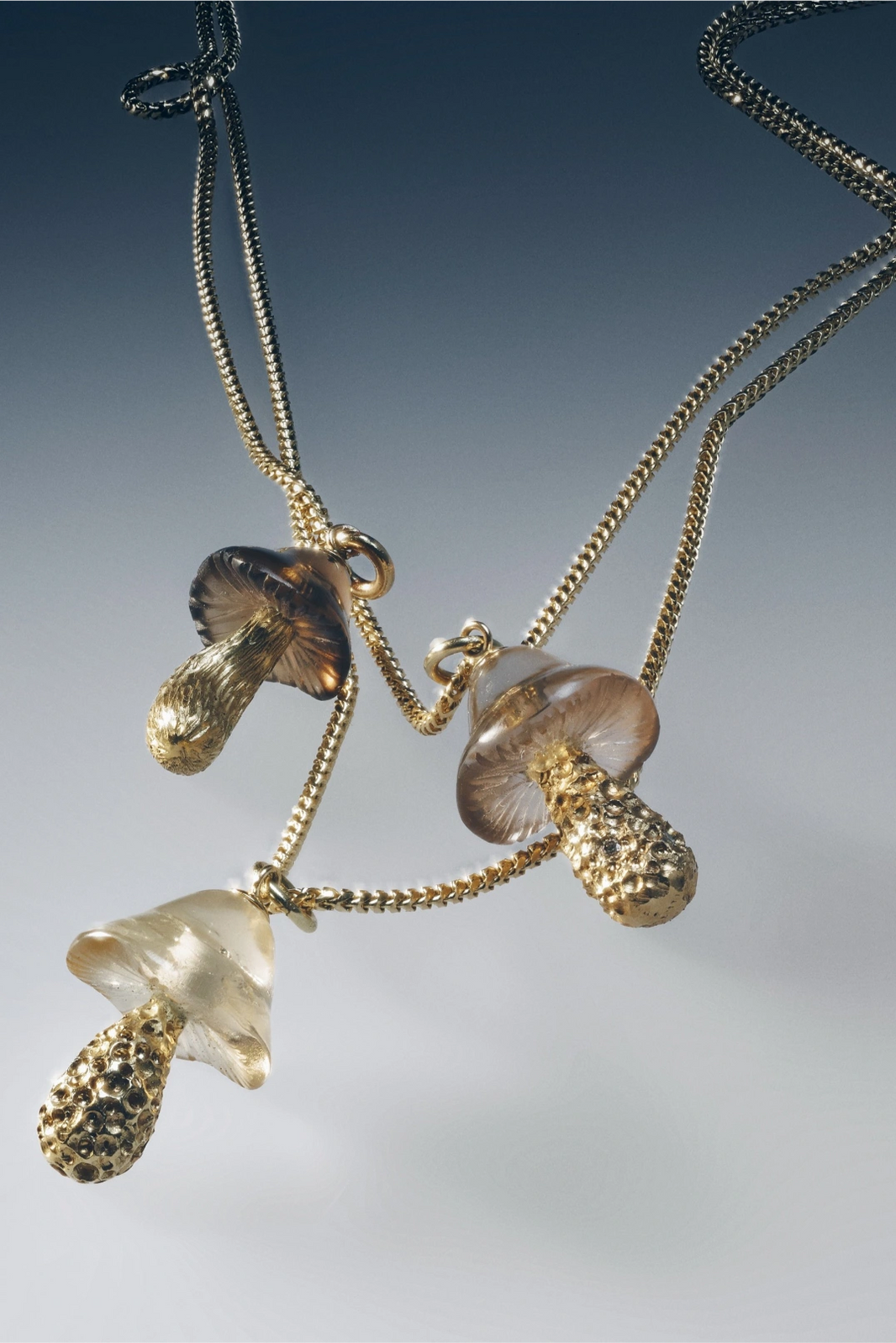Gold necklace with mushroom-shaped pendants on a gradient background
