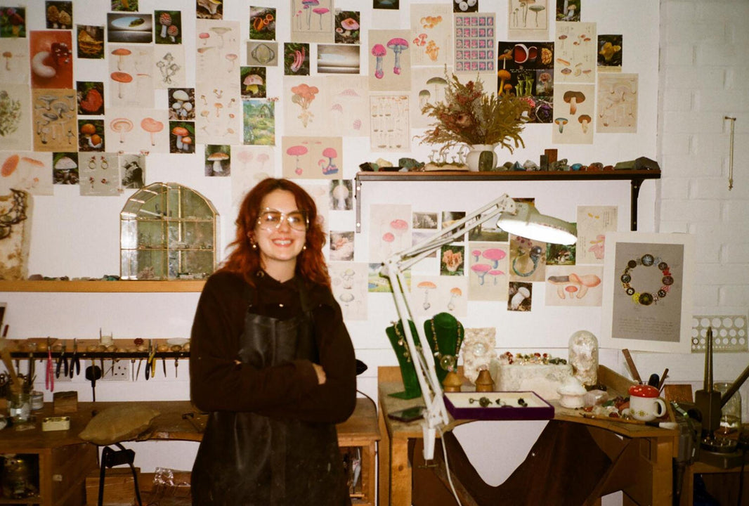 Person standing in a room with artistic decorations on the walls and a desk with various items.
