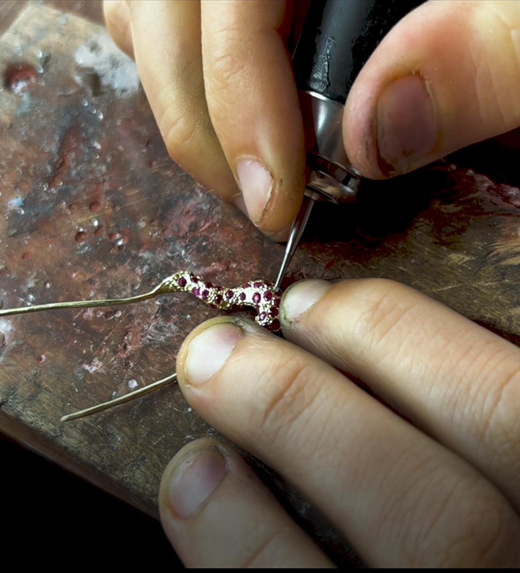 Close-up of hands working on a piece of jewelry with a tool.