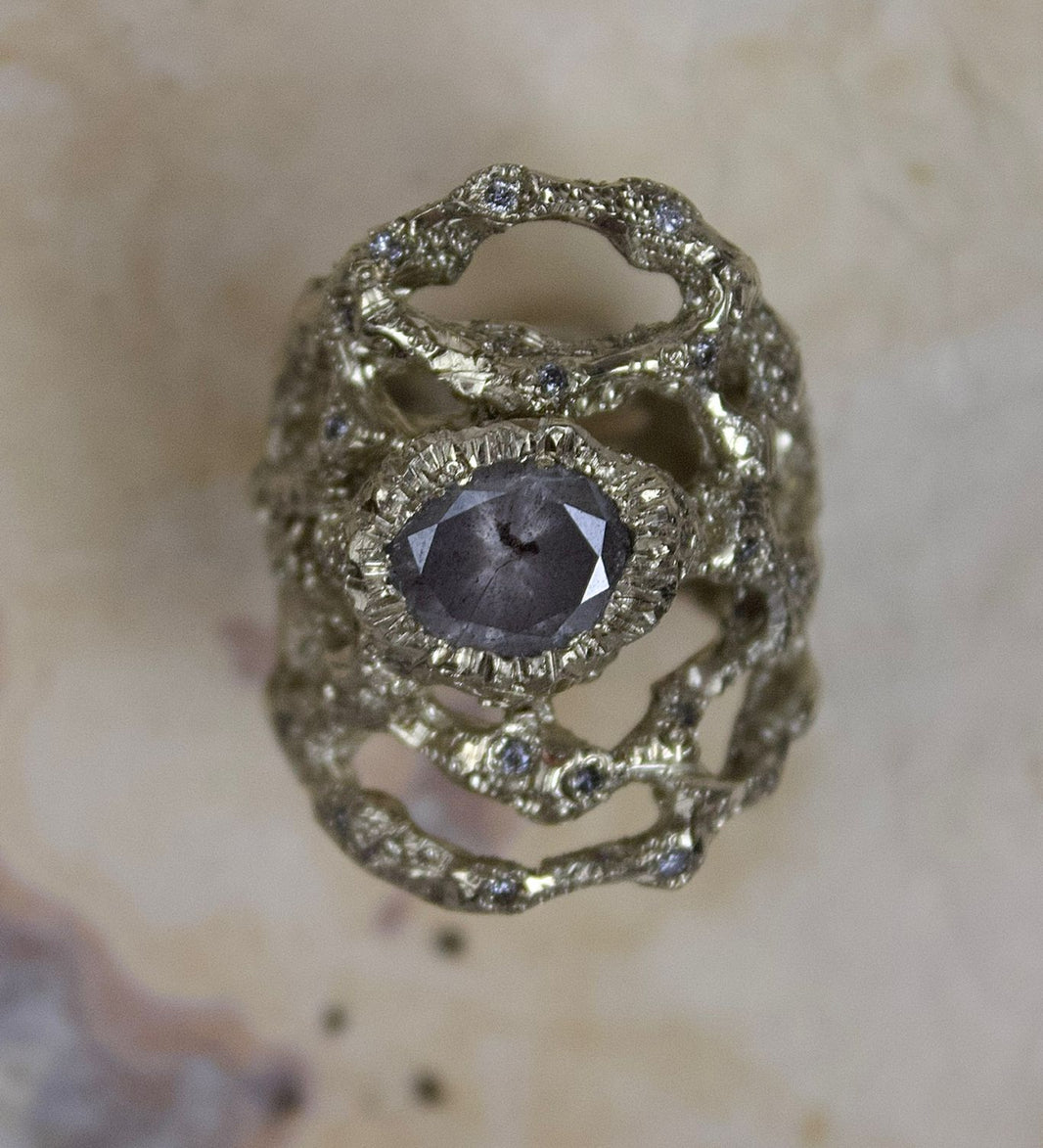 Gold ring with a central gemstone on a textured beige background